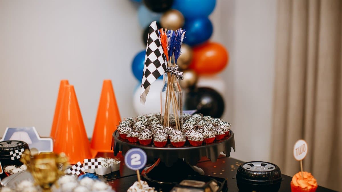 Racing themed party table with cupcakes, balloons, and checkered flags creating a festive atmosphere.