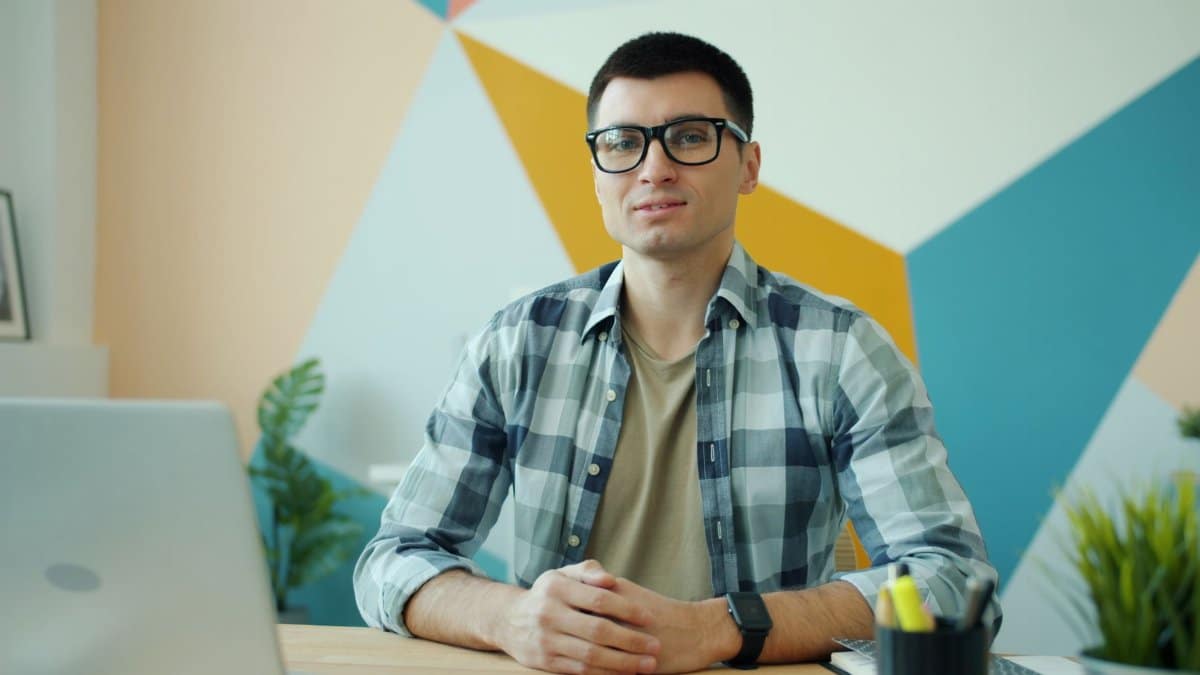 Portrait of a young professional man working at a desk in a modern office setting.