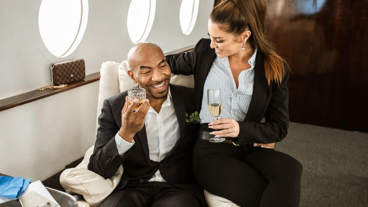 Couple in suits enjoying drinks in a private jet, symbolizing luxury and elegance.