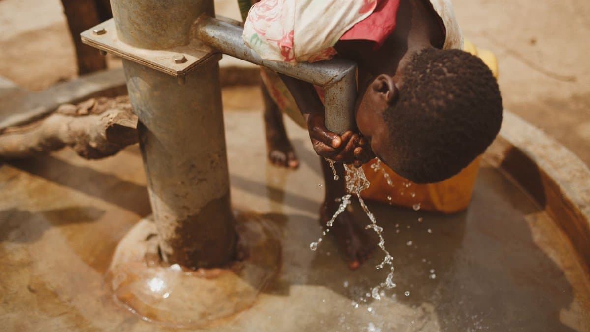 A girl bends to drink clean water from a well in Kitgum, Northern Uganda.