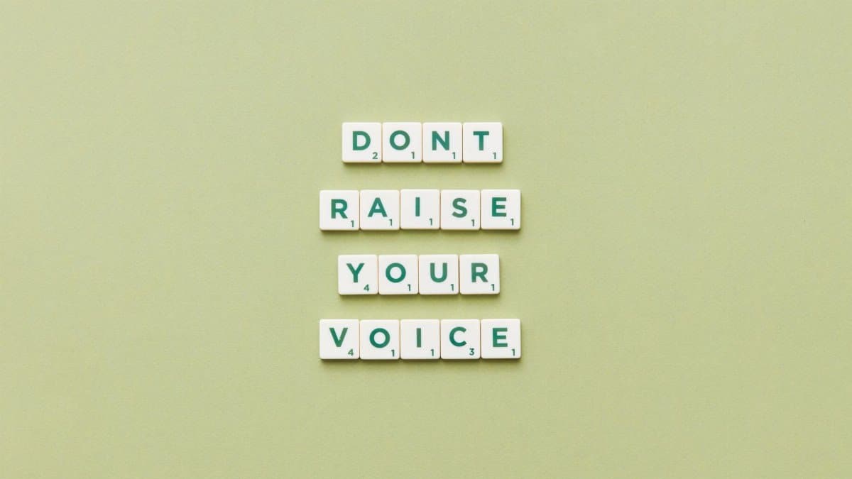 Scrabble tiles spelling 'Don't Raise Your Voice' on a green background.