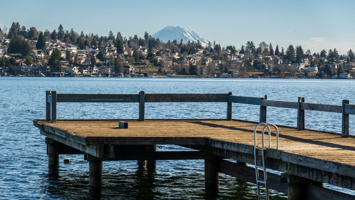 A scenic view of a pier extending into a lake with Mount Rainier in the background.