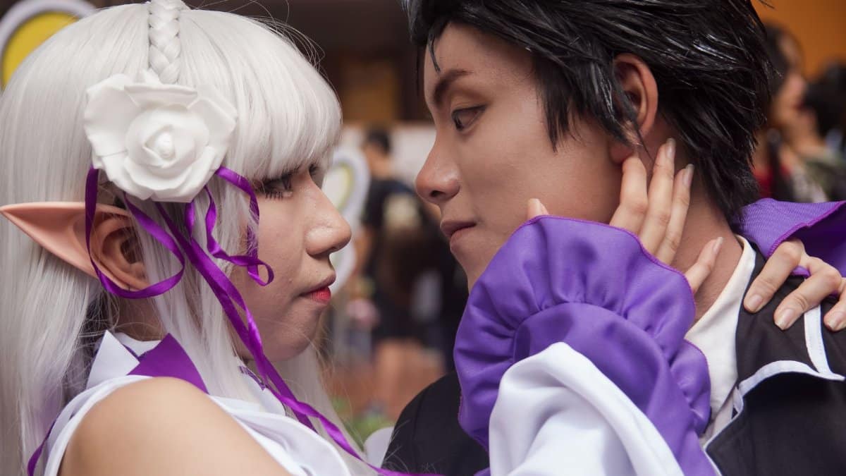 A couple in detailed cosplay costumes shares an intimate moment at a convention.