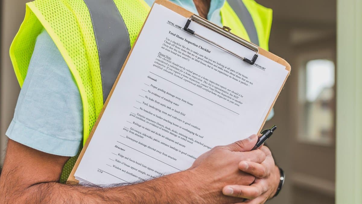 Close-up of home inspector holding a checklist on a clipboard with a pen.