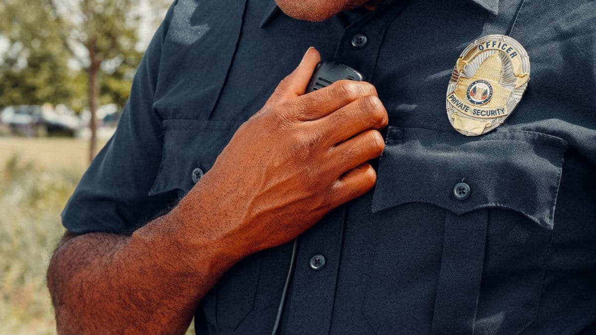 Close-up of a security officer using a radio outdoors, showcasing professional security attire.