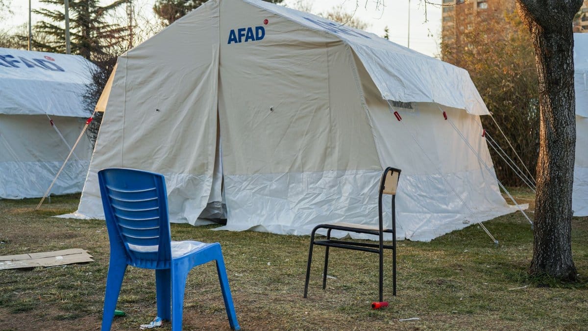 Emergency tents set up in Gaziantep for disaster relief efforts, featuring chairs and trees.