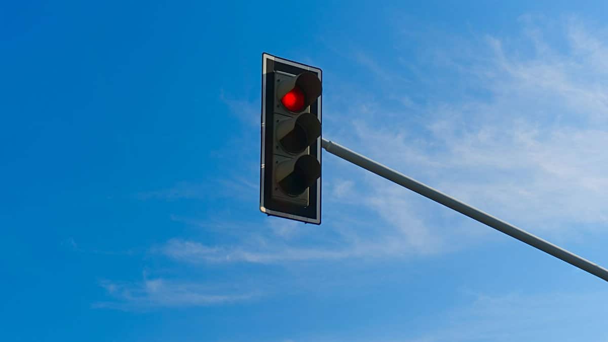 Traffic signal on red light with clear blue sky background.