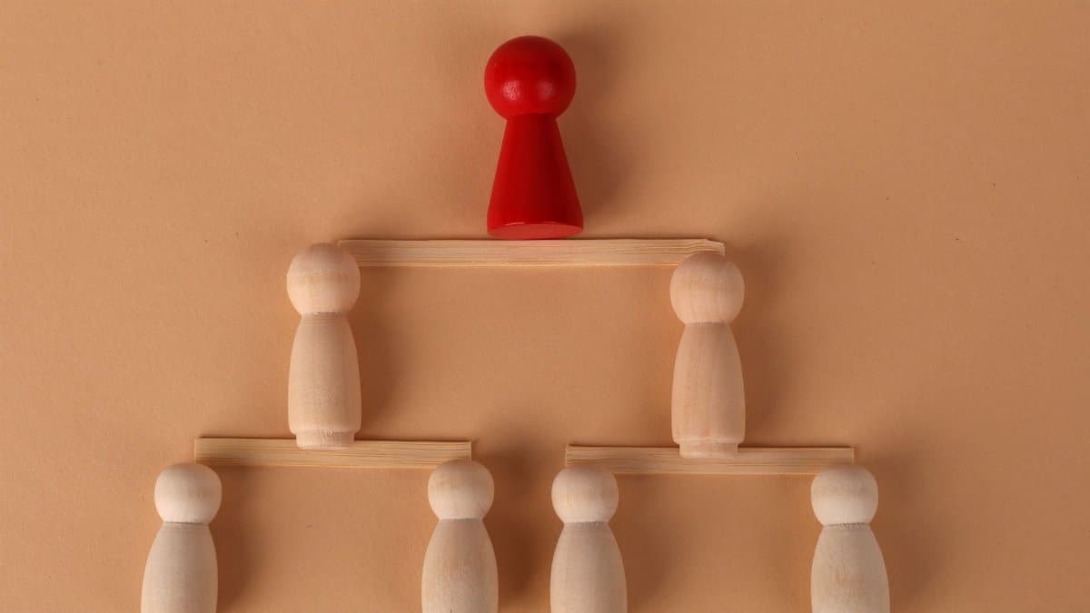 Wooden figures arranged to illustrate a hierarchical structure, symbolizing leadership and teamwork.