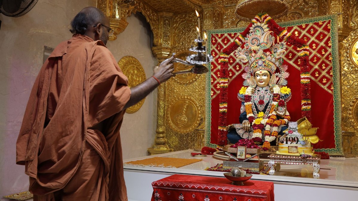 Hindu priest performs religious ceremony at ornate temple altar with deity in Poicha, Gujarat.