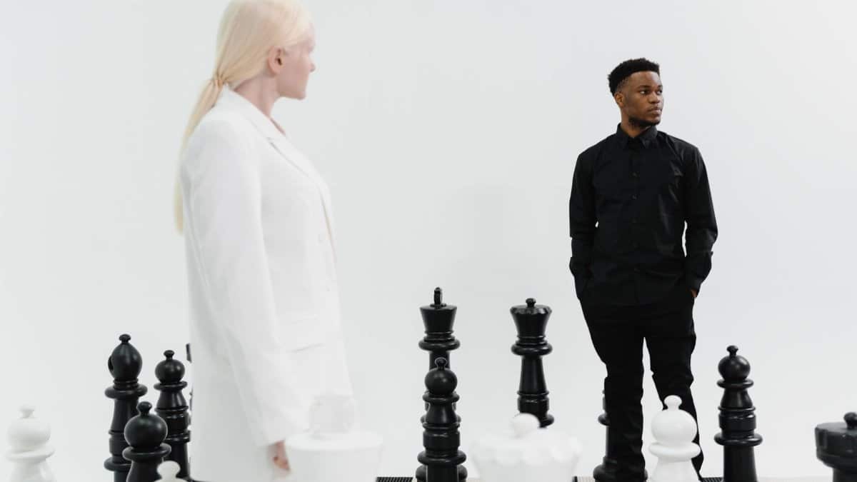 Two individuals strategize in a life-sized chess game, emphasizing competition and strategy.