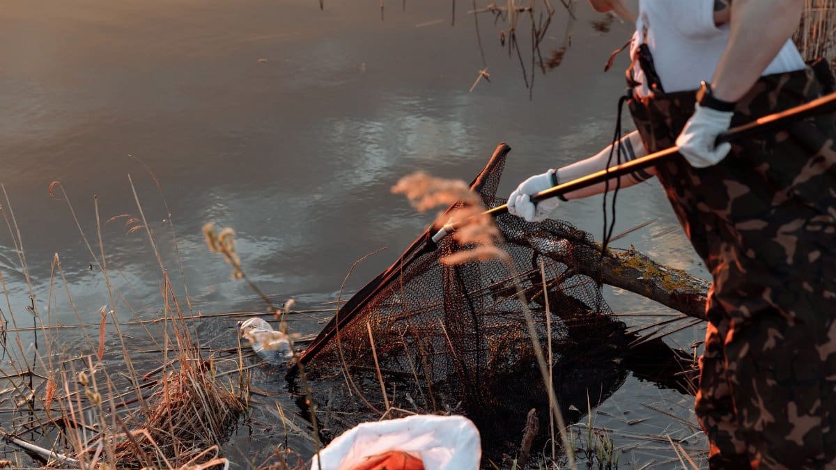 Person cleaning lake with net, promoting environmental awareness and conservation.