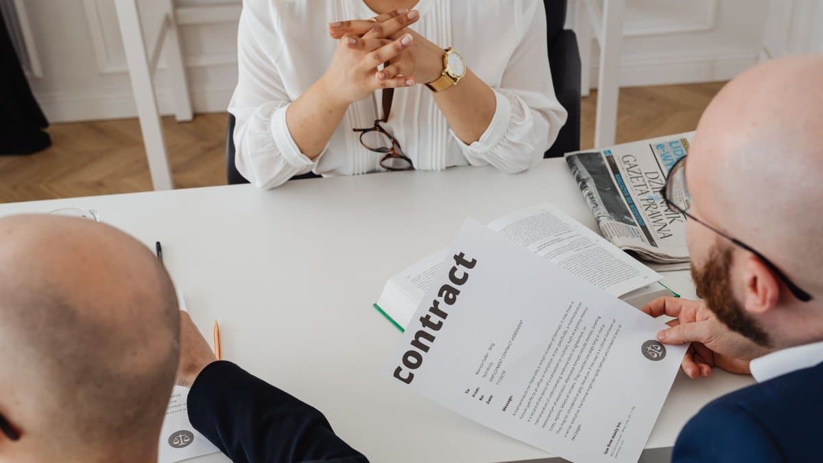 Business professionals discussing a contract in a modern office setting.