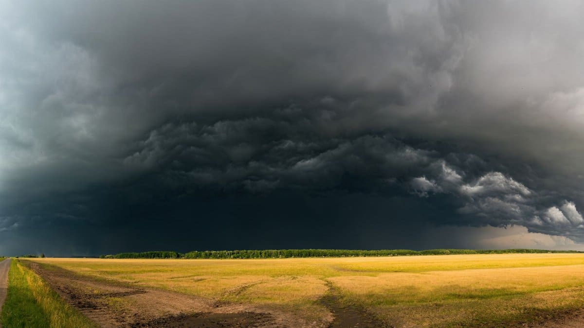 Photograph of storm clouds brewing over an expansive rural field, capturing the essence of weather dynamics.