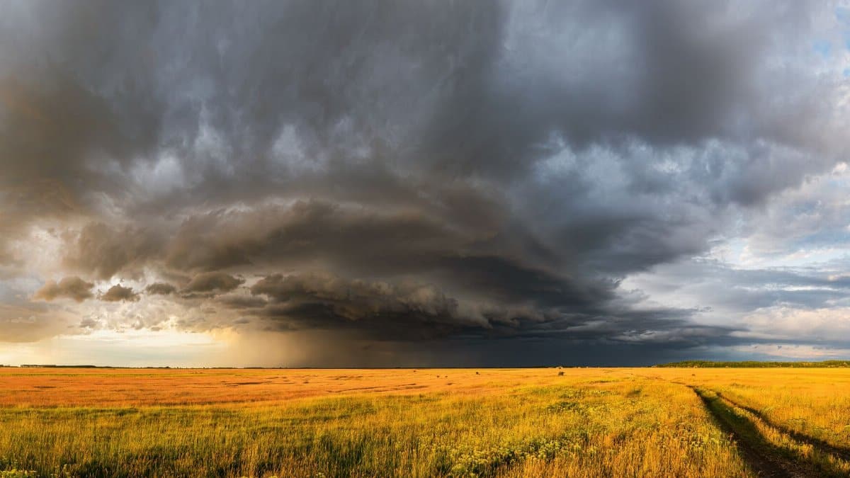 A vast countryside field under imposing storm clouds, showcasing dramatic weather.
