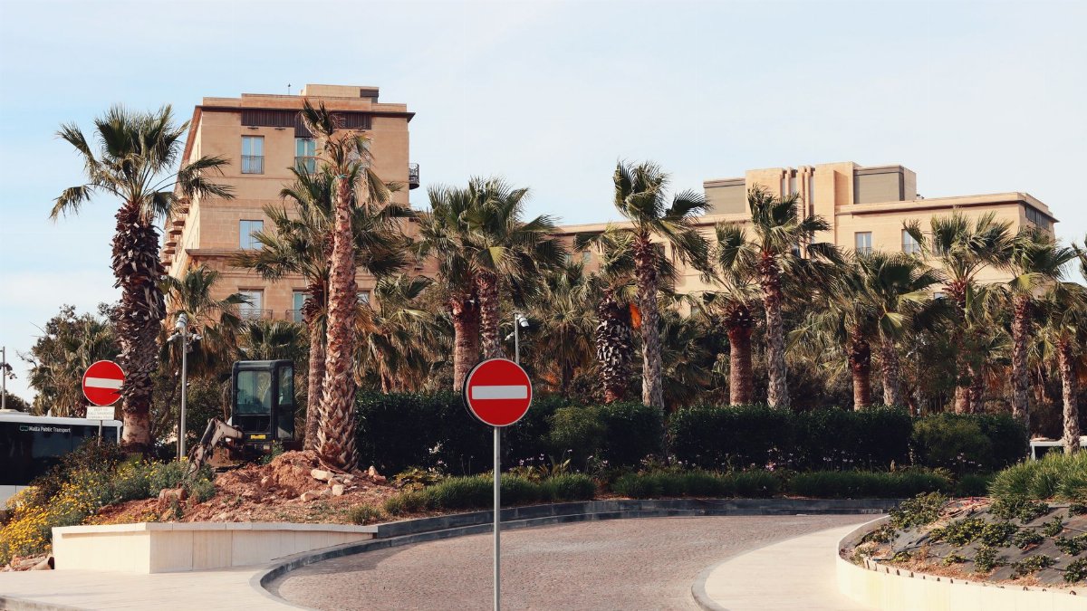 A sunny view of a traffic circle with palm trees and no entry signs in Valletta, Malta.