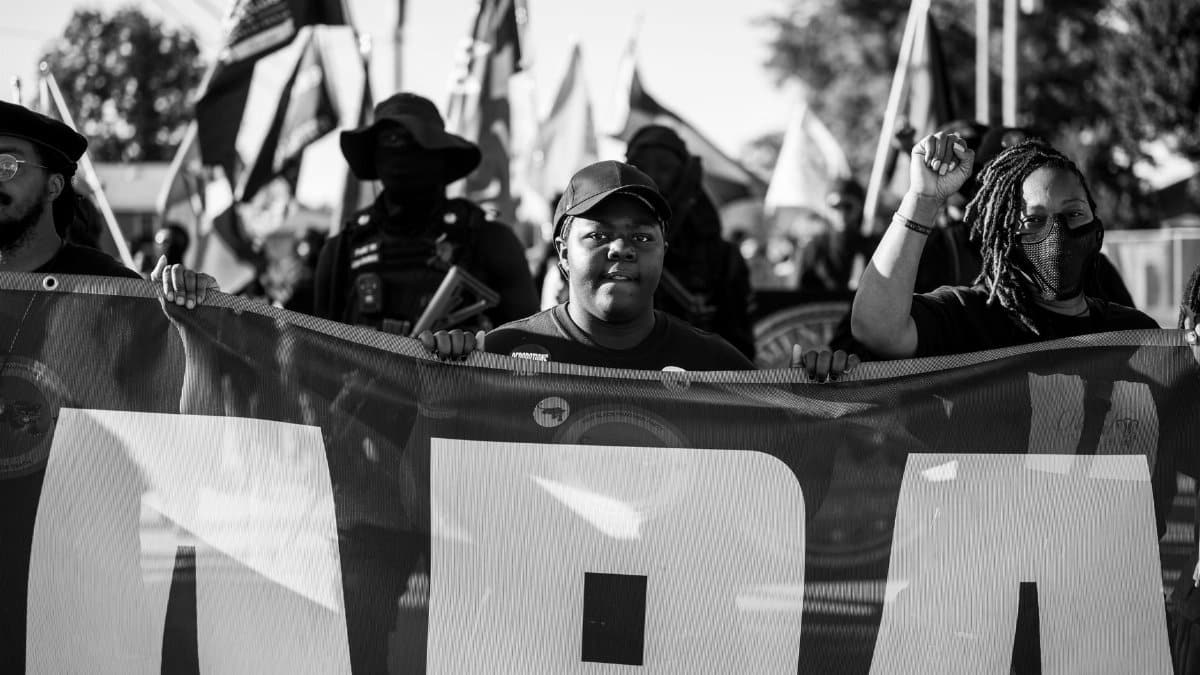 A powerful black and white image of protestors holding a banner during a demonstration in Tulsa, Oklahoma.