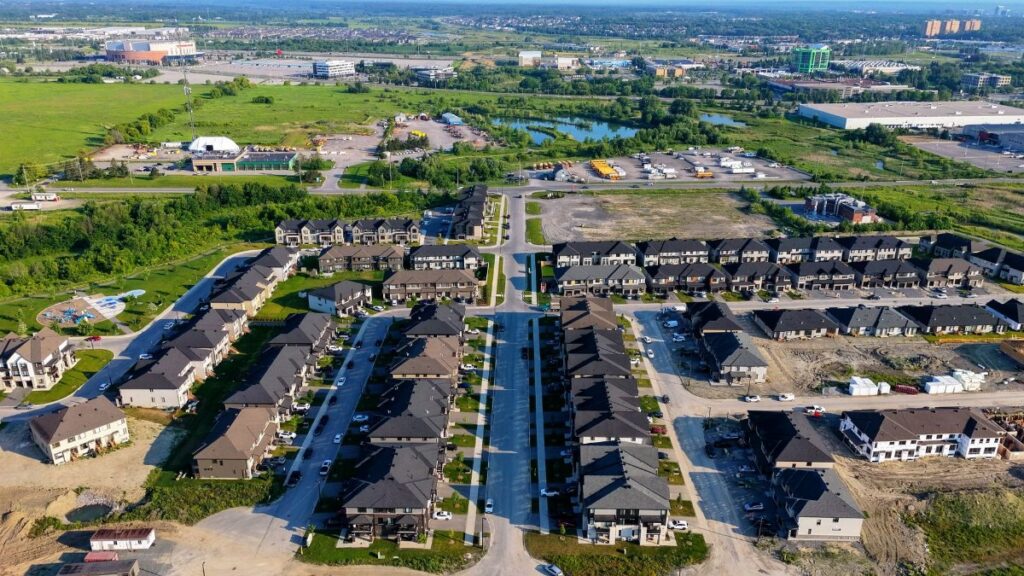 Aerial shot of a suburban neighborhood with rows of houses during the day.