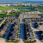 Aerial shot of a suburban neighborhood with rows of houses during the day.