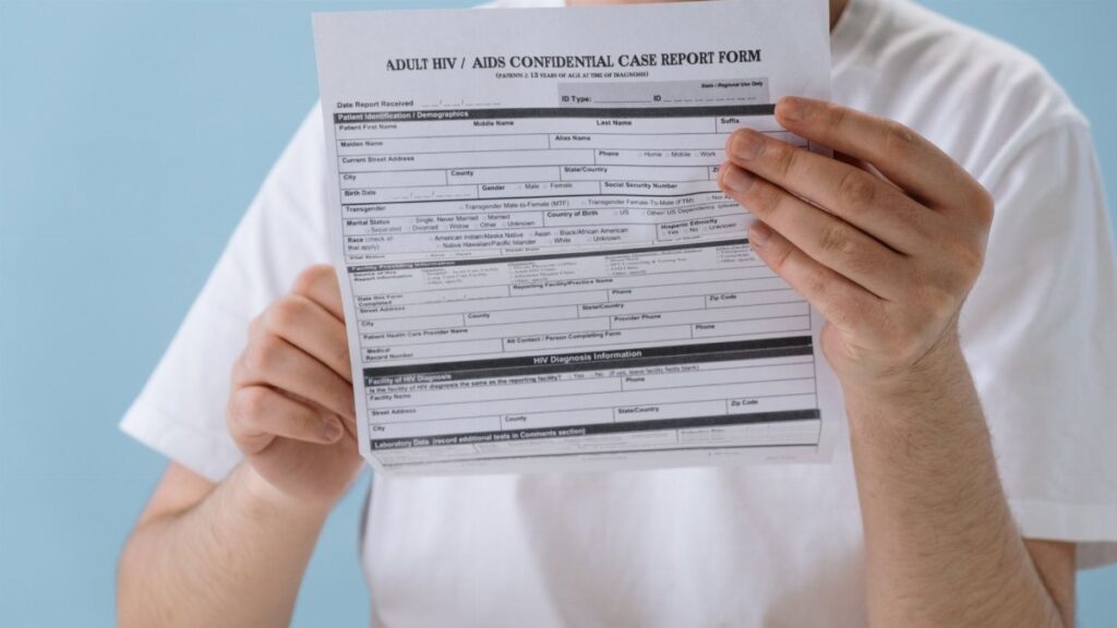 Person holding confidential HIV/AIDS case report form, symbolizing health awareness and privacy.
