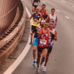 A group of male athletes competing in a city marathon, featuring diverse runners and dynamic movement.