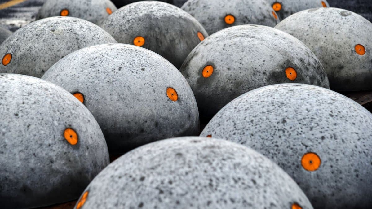 Close-up of concrete spheres with orange reflective discs for road safety.