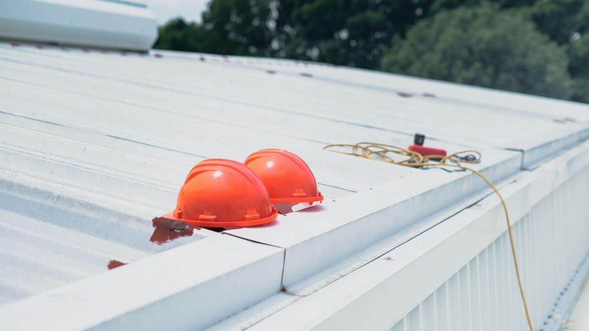 Red hard hats and safety equipment on a metal roof, emphasizing construction safety.