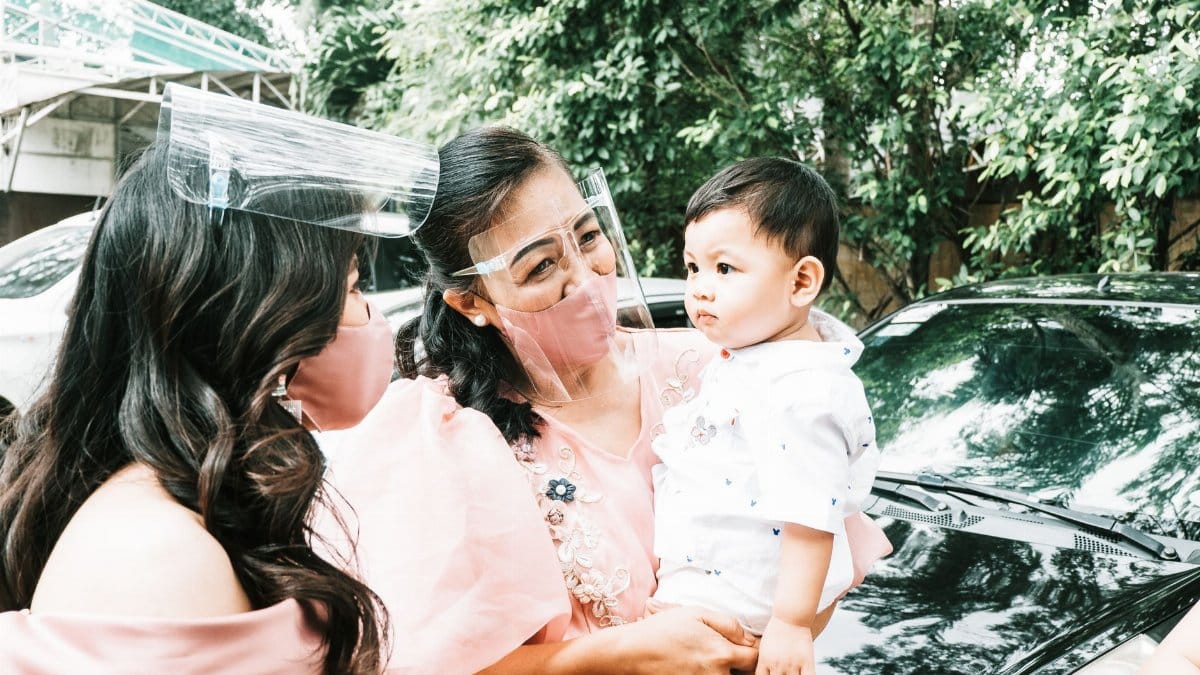 A family outdoors wearing face masks and visors for safety during the pandemic.
