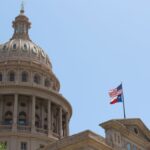 Low angle view of the Texas State Capitol dome and flags in Austin, Texas.