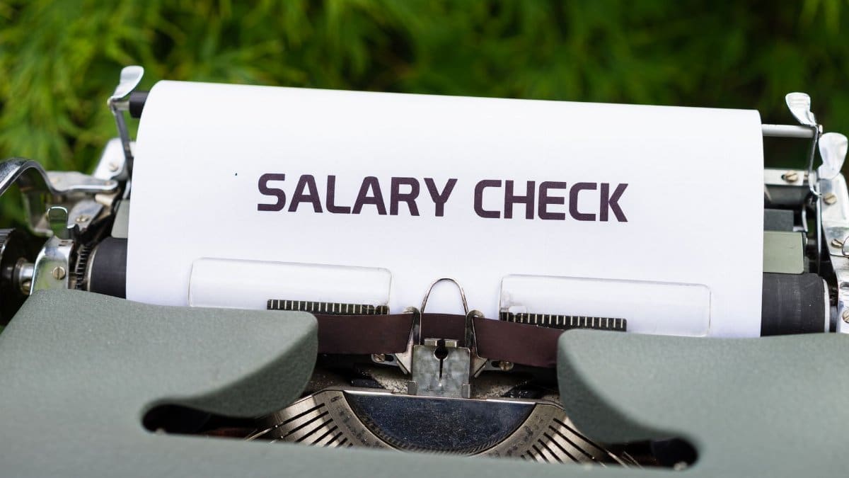 Close-up of a vintage typewriter typing 'Salary Check' on paper, symbolizing payroll and finance.