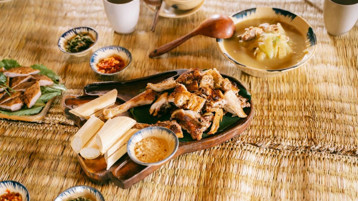 A delicious spread of traditional Asian dishes served on a bamboo mat with a rustic setting.