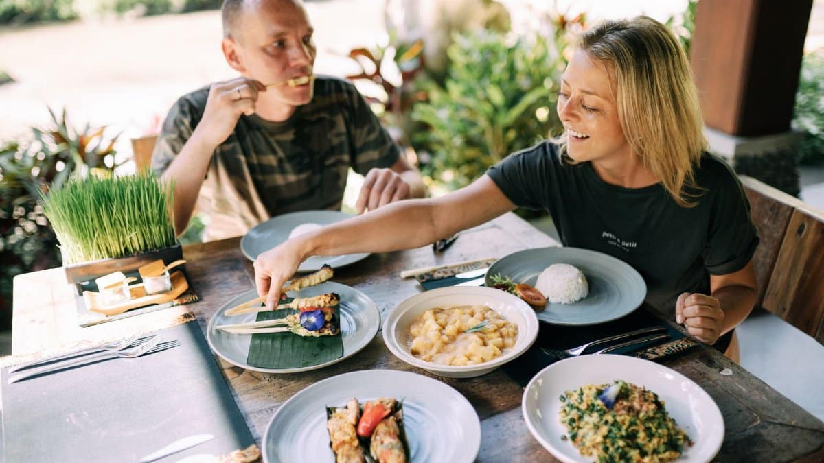 A couple enjoying a variety of Asian dishes outdoors at a cozy table setting.