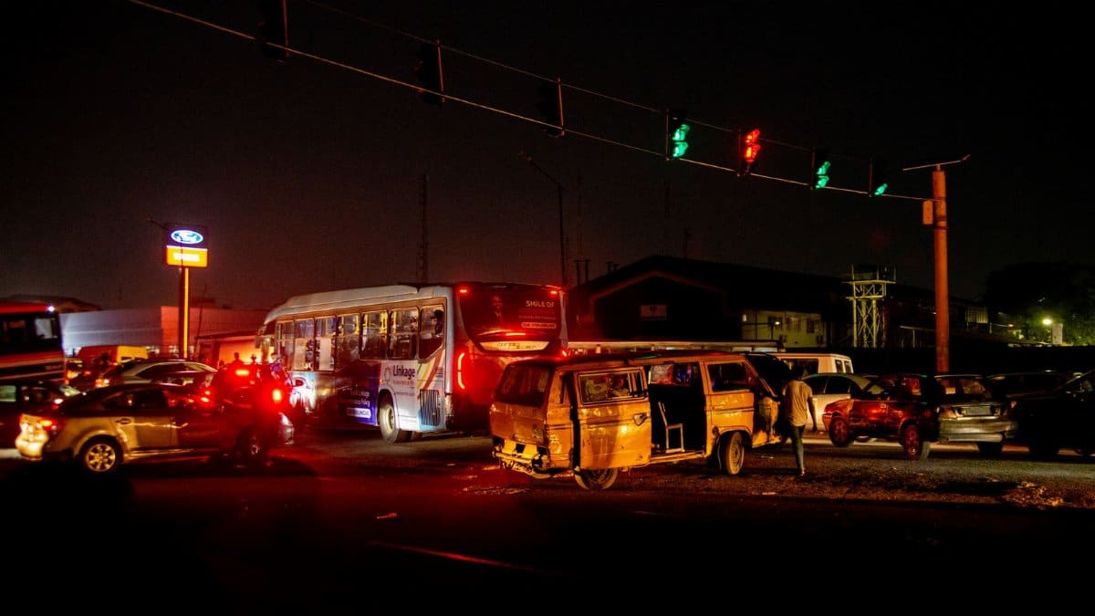 A crowded urban nighttime scene featuring a traffic accident at a busy intersection.