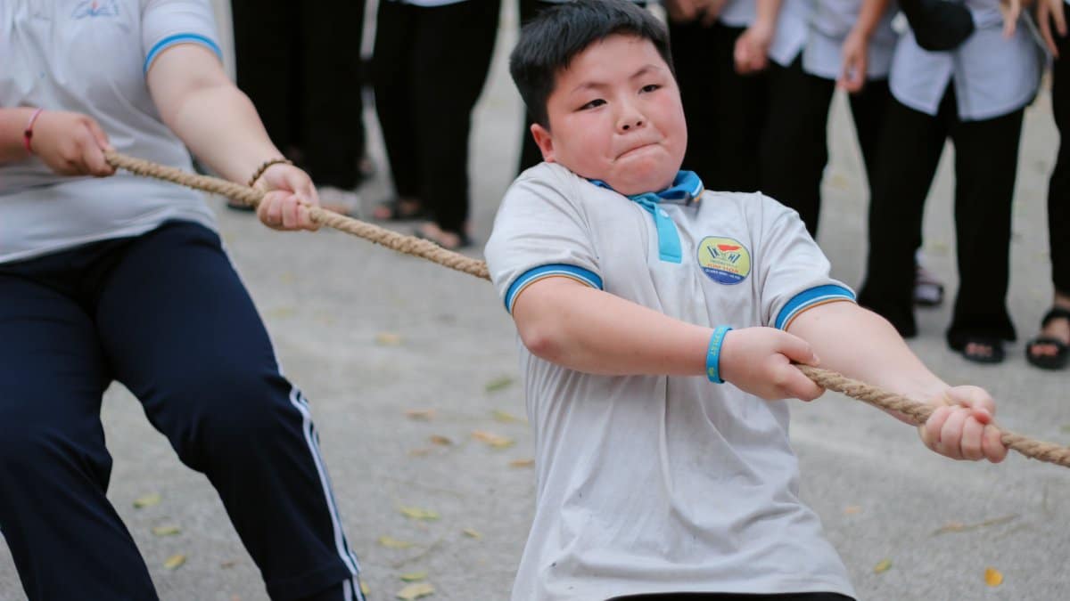 Focused students in a tug-of-war game during a school sports event.