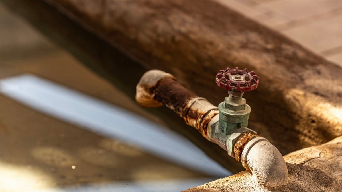 Close-up of a rusty water valve with reflections in a Dubai setting, highlighting decay and water themes.