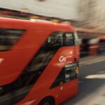 Blurred motion of a classic red London bus speeding through a busy street, capturing city life energy.