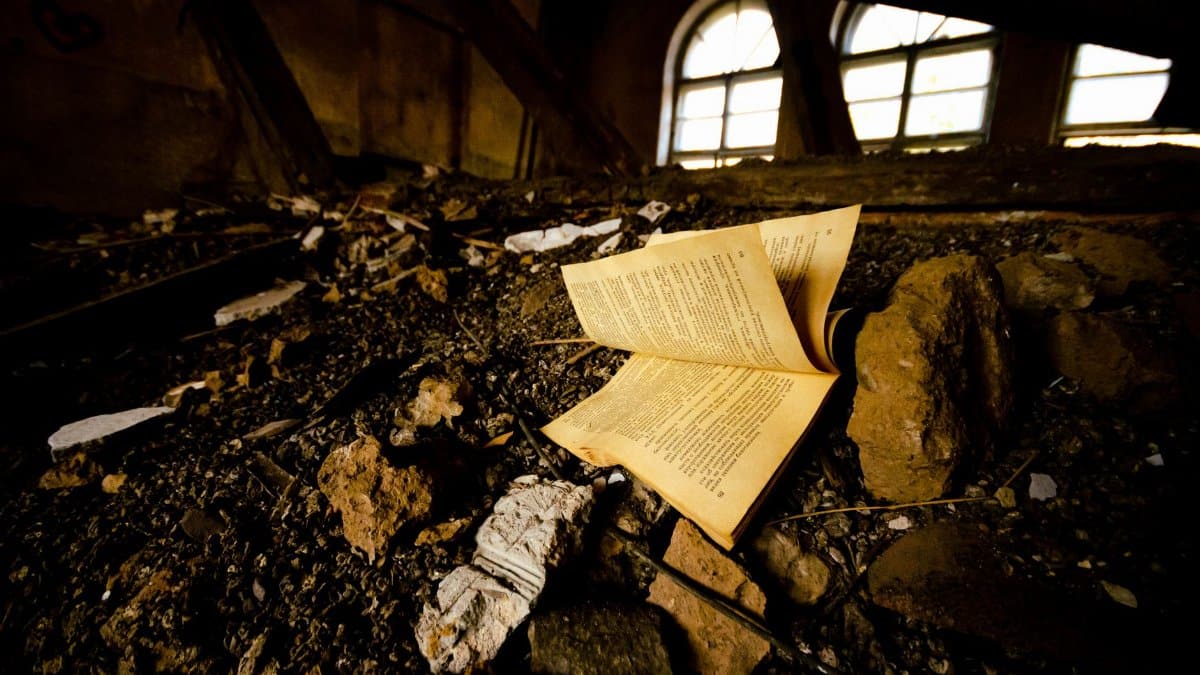 An old book lies amidst ruins and decay in an abandoned building.