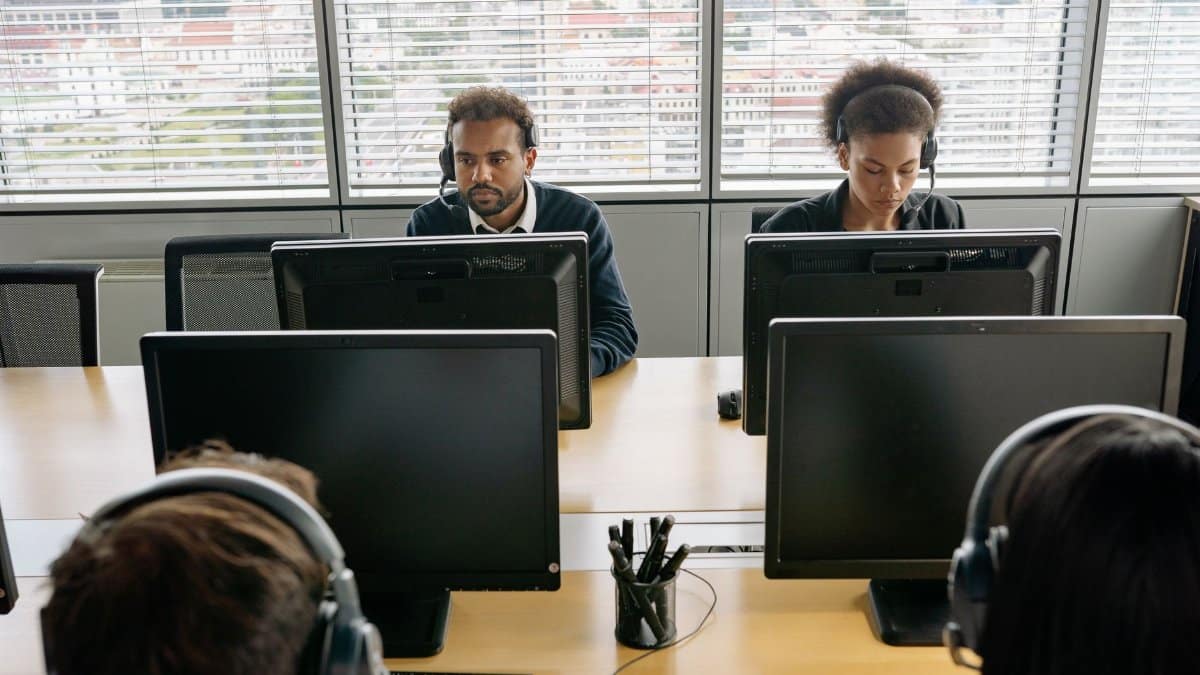 Group of call center agents working on computers in an office environment.