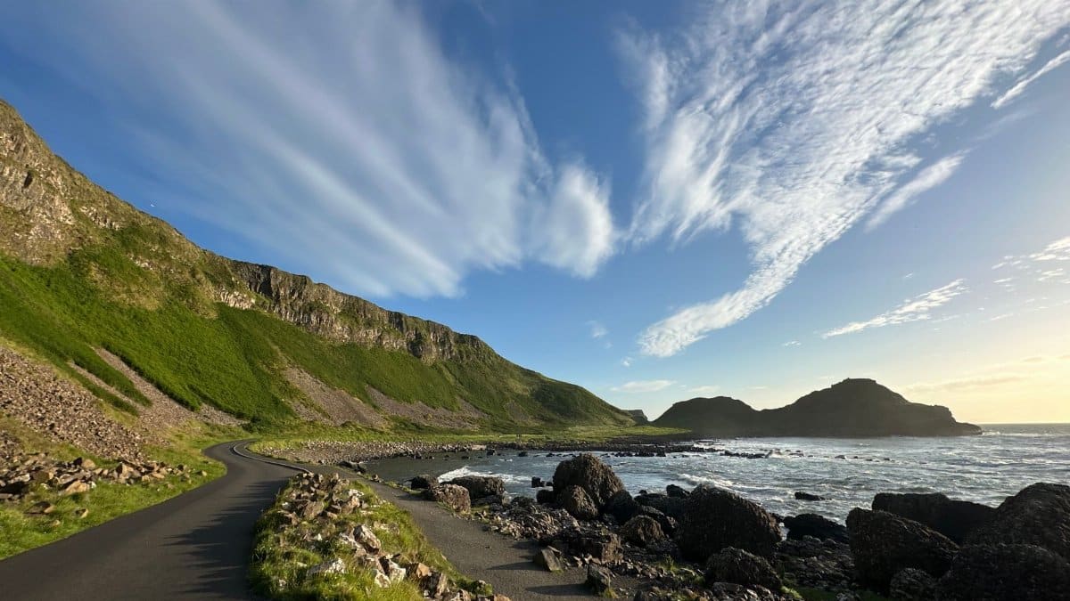 A winding road along the coast of Northern Ireland with stunning cliffs and the Atlantic Ocean under a vibrant sky.