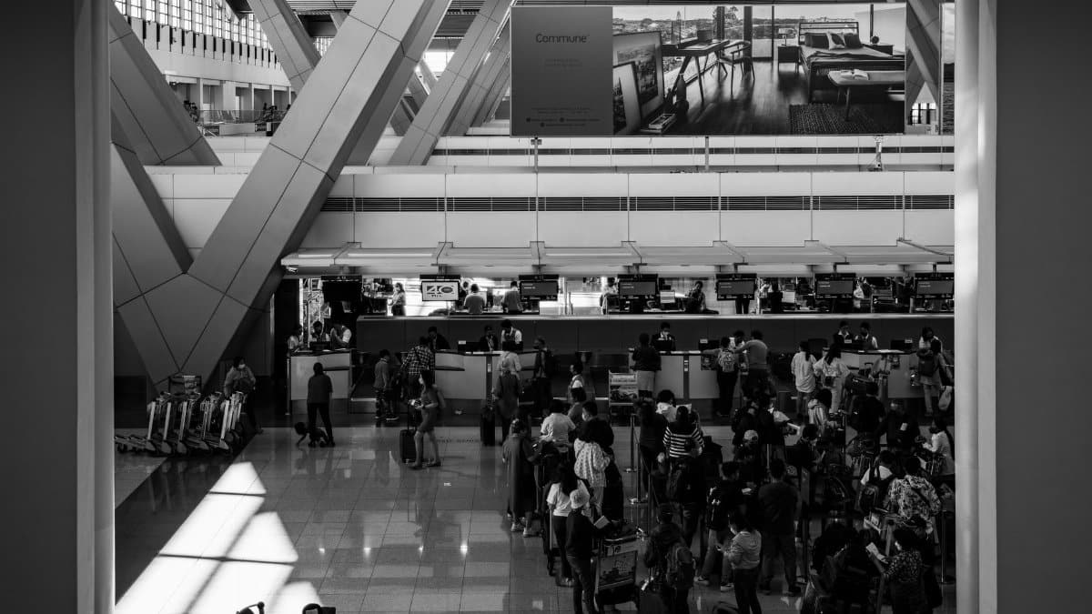 Black and white image of travelers at a bustling airport in Pasay, capturing the essence of global travel.