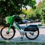 Lime bike parked on a sunny street in Seattle, offering a green transportation option among lush trees.