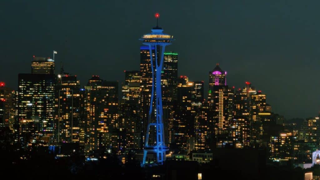 The iconic Space Needle illuminating the Seattle skyline at night with city lights aglow.