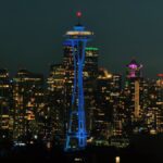 The iconic Space Needle illuminating the Seattle skyline at night with city lights aglow.