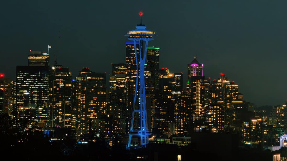 The iconic Space Needle illuminating the Seattle skyline at night with city lights aglow.