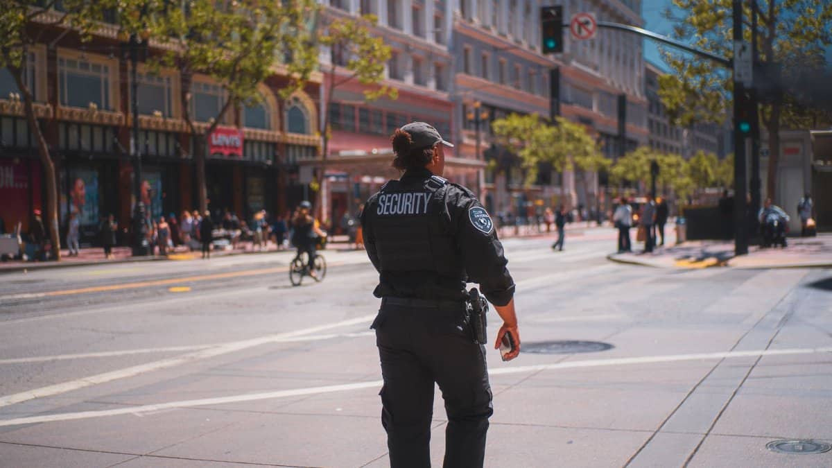 A security officer patrols a bustling street in San Francisco, capturing daily urban life.