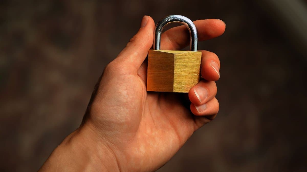 Hand holding a brass padlock, symbolizing security and protection