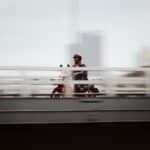 A motorcyclist rides across a bridge in Bangkok with a dynamic motion blur effect.