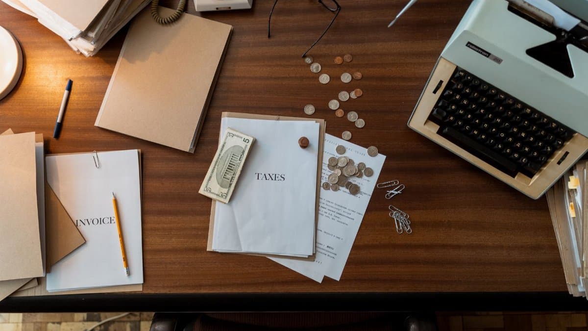 Retro office scene featuring a typewriter, coins, documents, and stationary on a wooden desk.