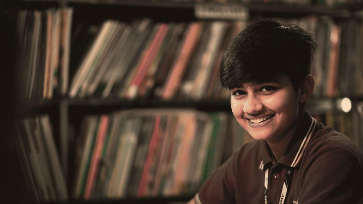 Joyful teenager smiling in a library, creating a warm academic atmosphere.