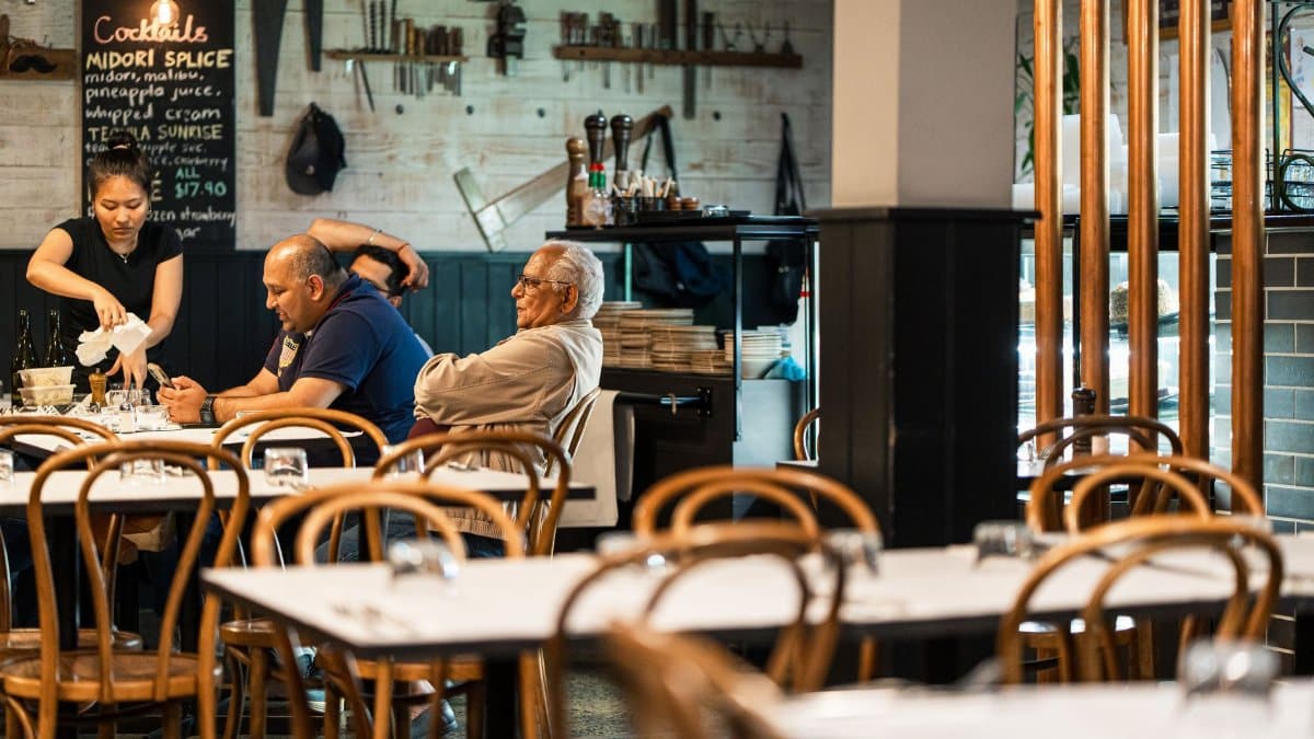 A relaxed dining scene at a Melbourne restaurant with diverse patrons enjoying their meal.