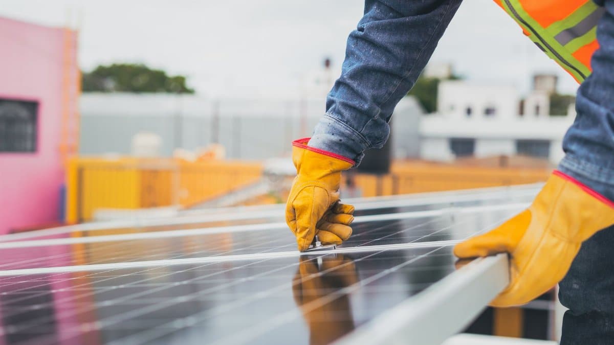 A solar technician performing maintenance on solar panels outdoors.